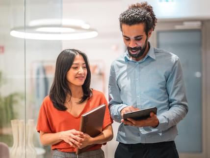 two colleagues walking down a hall reviewing tablet