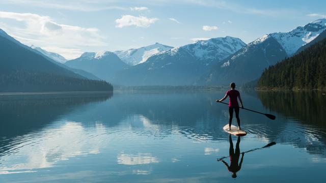 paddle boarder in lake surrounded by mountains