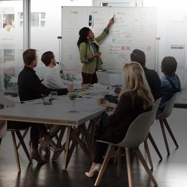 Woman presenting at whiteboard to colleagues in office