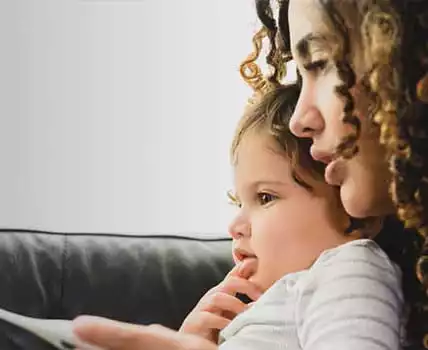 mother holding child while looking at mobile phone