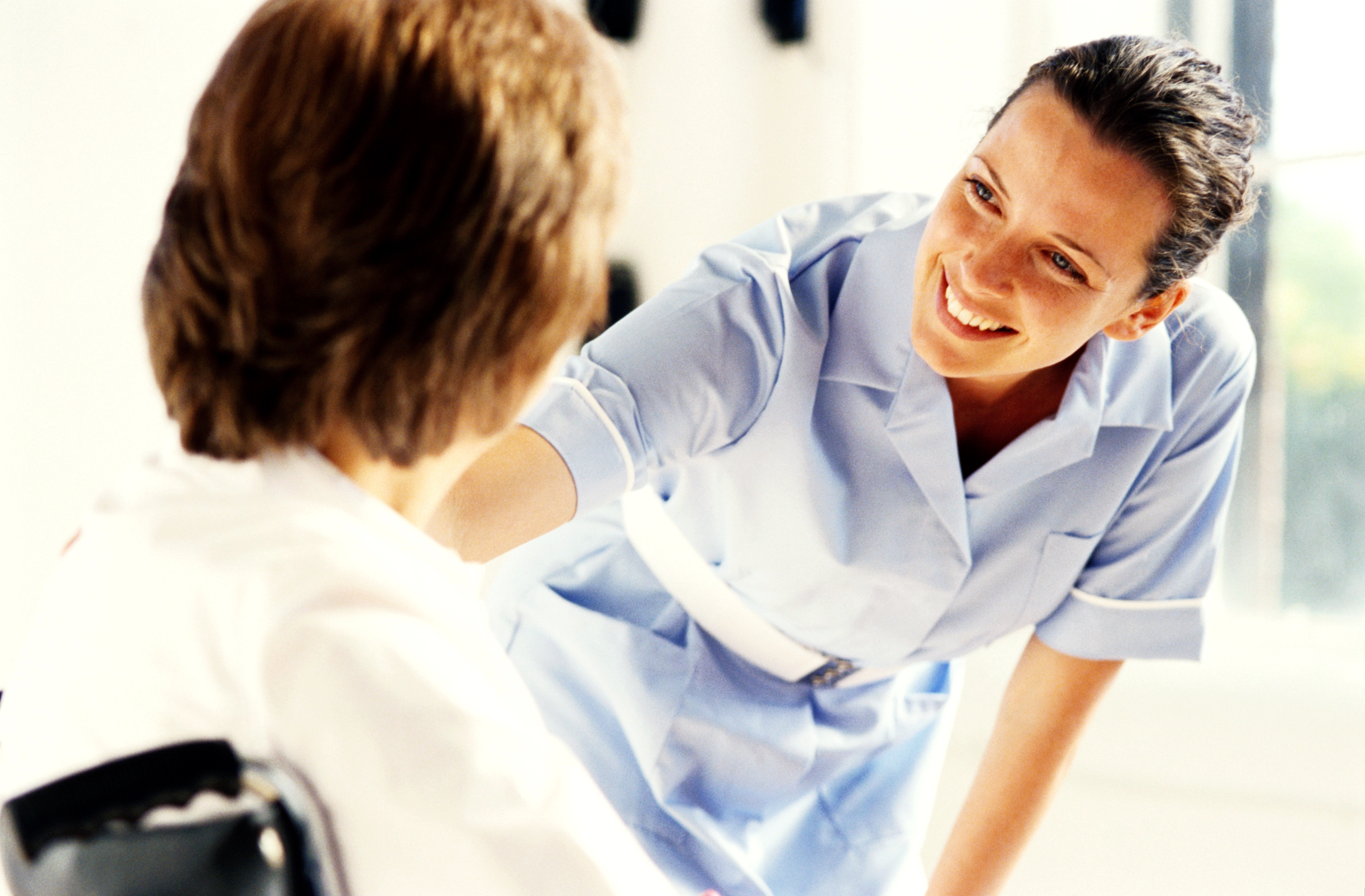 Young female nurse talking to a patient in a wheelchair