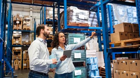 Manager working with foreman in warehouse checking stock levels.