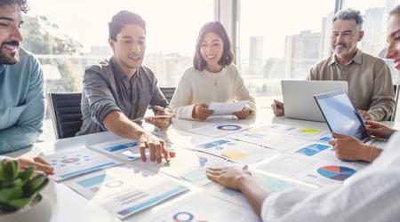 Group of people working with Paperwork on a board room table at a business presentation